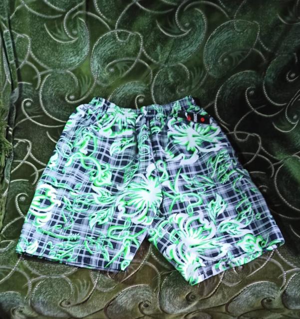 Новые мужские короткие шорты в черно-белую клетку с зеленым орнаментом.